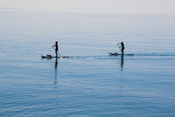 Deux personnes sur la mer en train de faire du paddle