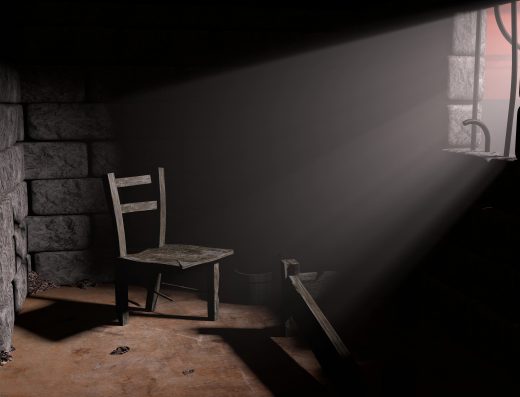 Chaise en bois dans une cellule sombre éclairée par un rayon de lumière venant d’une fenêtre grillagée.
