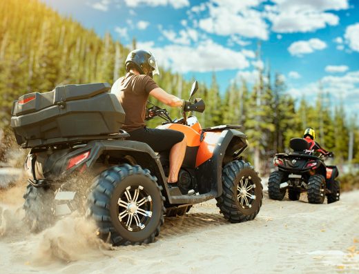 Deux personnes en randonnée en quad sur un chemin sableux en pleine nature.