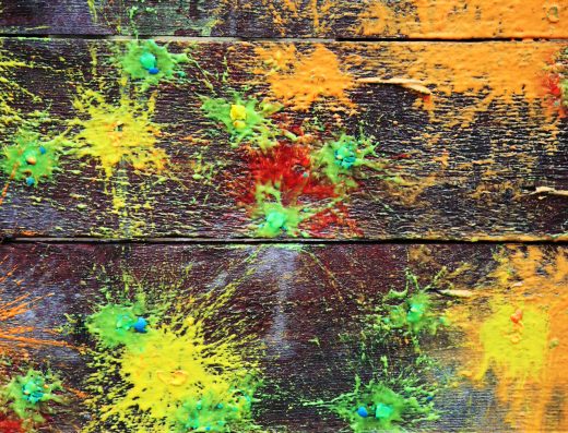 Traces colorées de billes de paintball éclatées sur une surface en bois