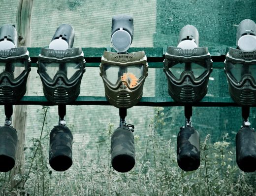Rangée de masques et lanceurs de paintball alignés, dont un avec une éclaboussure de peinture
