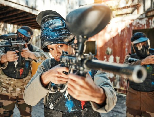 Joueurs de paintball visant avec leurs lanceurs lors d’une partie en terrain extérieur