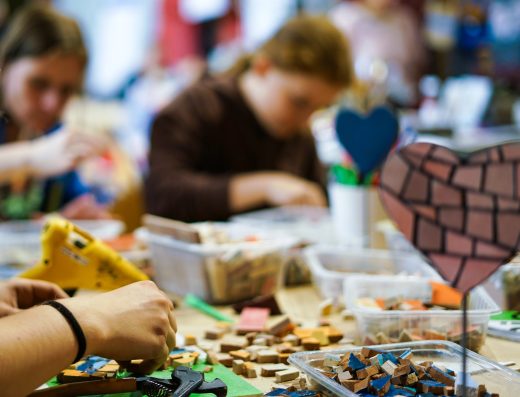 Participants réalisant une mosaïque lors d’un atelier créatif, avec des tesselles colorées sur la table.